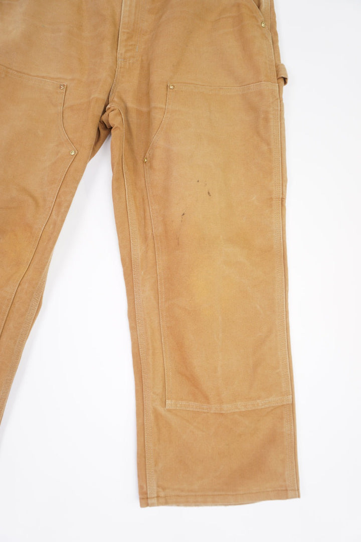 Tan Carhartt heavy duty cotton carpenter jeans with multiple pockets and double knee