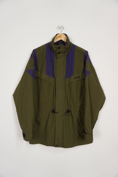 Vintage khaki green Adidas windbreaker style jacket, with embroidered logo on the chest and multiple zip up pockets