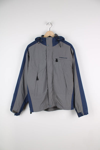 Grey and blue Timberland coat with embroidered logo on the chest. Features detachable fleece lining.