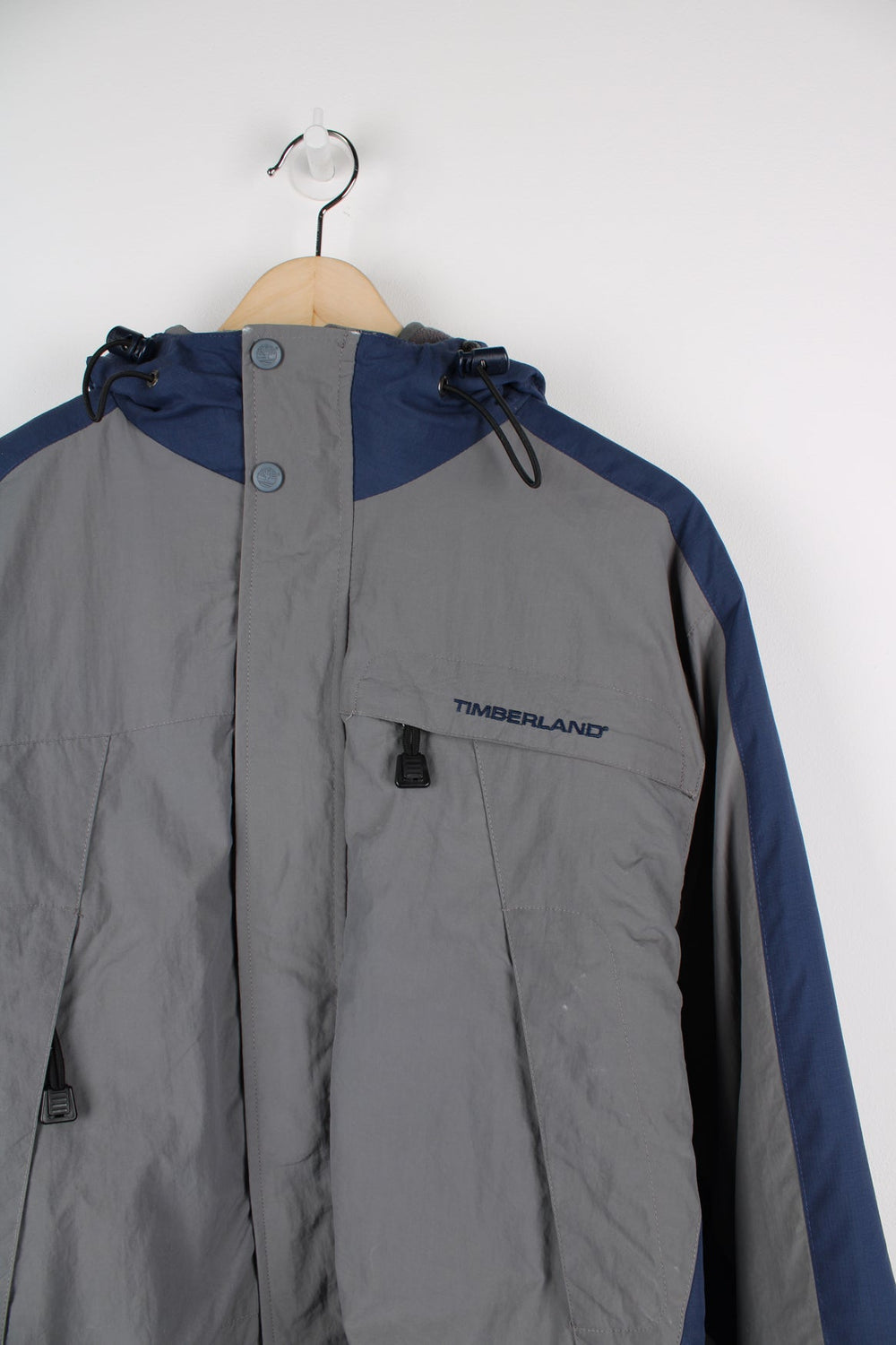 Grey and blue Timberland coat with embroidered logo on the chest. Features detachable fleece lining.