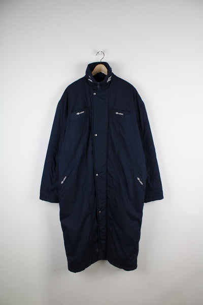 Blue Umbro maxi longline coat. Features pockets on the chest and embroidered logo on the neck.
