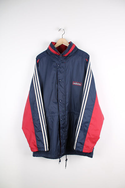 Blue and red Adidas coat featuring embroidered logo on the chest and classic three stripes down each sleeve.