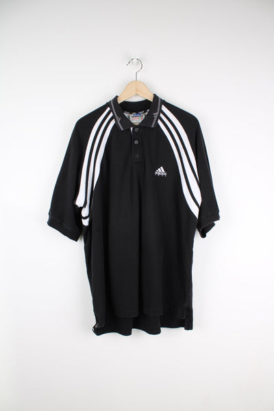 Black Adidas polo shirt with embroidered logo on the chest and stripe feature down each arm.