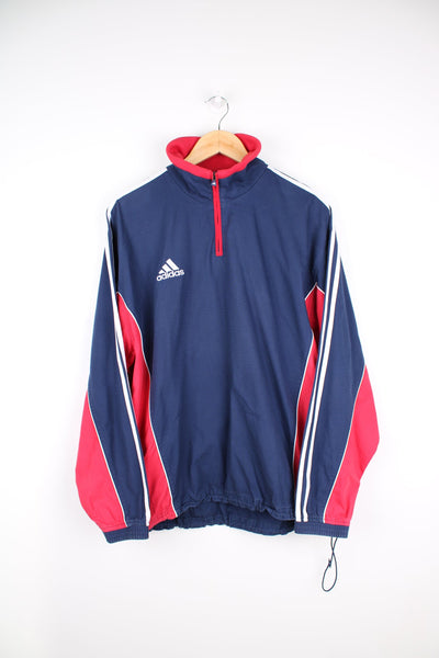 Vintage 90s blue and red Adidas quarter zip pullover tracksuit top. Features embroidered logo on the chest and signature three stripe detail down the sleeves.