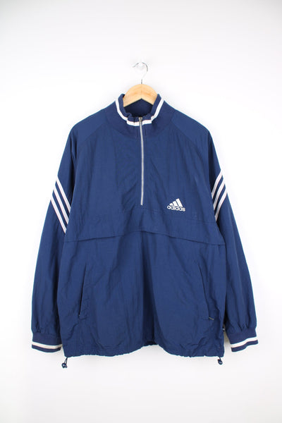Blue Adidas pullover tracksuit jacket with quarter zip. Features embroidered logo on the chest and signature three stripes on each sleeve.