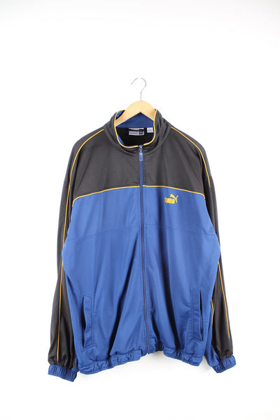 Blue and black Puma tracksuit top with embroidered logo on the chest and yellow piping detail.