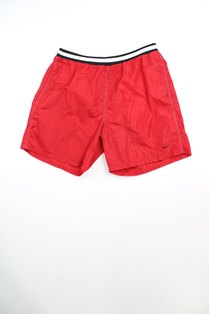 Red Nike swim shorts with elasticated drawstring waist and embroidered logo. 