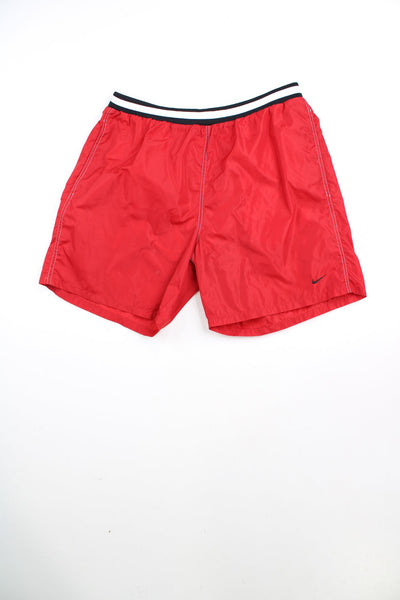 Red Nike swim shorts with elasticated drawstring waist and embroidered logo. 