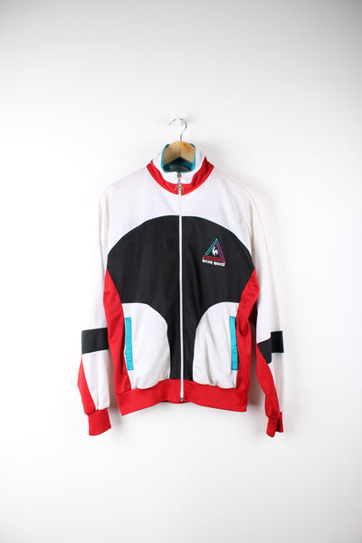 Vintage Le Coq Sportif tracksuit top in white, black, red and blue. Features embroidered logo on the chest.
