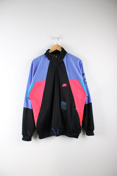Vintage Nike tracksuit top in black with pink, purple and blue panel details. Features embroidered logo on the chest and sleeve.