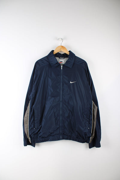 Vintage Nike 90s windbreaker tracksuit top in blue and grey. Features embroidered logo on the chest.