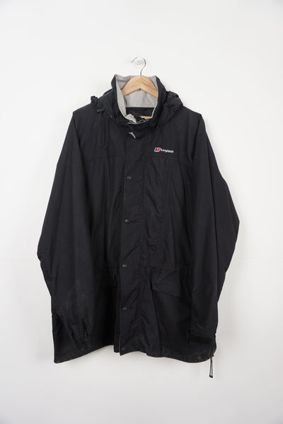 All black Berghaus zip through waterproof jacket with multiple pockets, foldaway hood and embroidered logo on the chest
